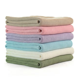 Stack of folded baby blankets in pastel colors on a white background