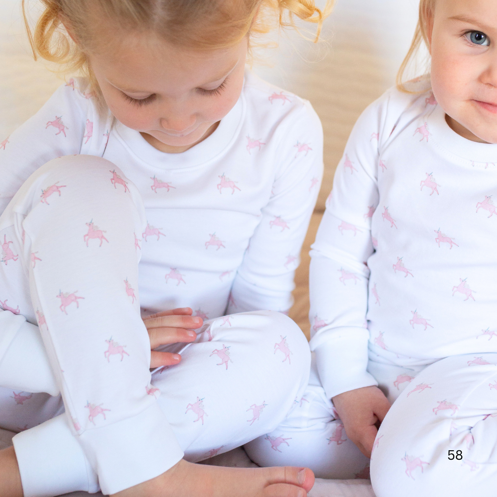Two children wearing matching pajamas with a pink pattern on a beige background